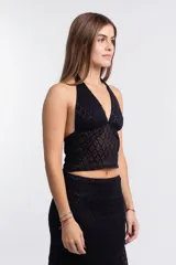 Top negro de corte halter con escote pronunciado en V y textura de encaje con patrón de rombos. El tejido es semitransparente.