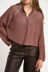 Sweater de punto morado con cierre metálico parcial en el cuello alto y mangas largas.