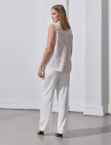 Camisa sin mangas de lino a rayas verticales azules y blancas, con cuello con solapa, escote en V, abertura central con botones y bolsillo en el pecho.