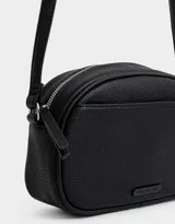 Bandolera negra de cuerina con bolsillo frontal con tag de metal, correa regulable, cierre superior y tirador de material principal.