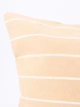 Funda de almohadón rectangular color beige con rayas horizontales blancas.