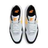 Championes Nike Air Max 1 de hombre, color blanco con detalles en gris, negro y naranja. Presentan la tecnología Air Max en la suela para mayor amortiguación.