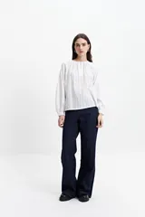 Blusa blanca de manga larga con detalle de tablas en el frente y puños.