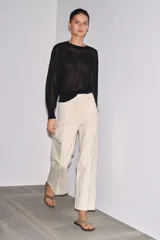 Jeans de tiro alto, pierna ancha y largo al tobillo, en denim celeste claro con efecto lavado. Presenta costura marcada en el centro de cada pierna y cierre frontal con cremallera y botón.