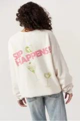 Buzo blanco de polar ultrasuave con cuello redondo, corte holgado y hombros caídos. Estampado frontal con texto "Capri Cocktail Club" en rosa y dibujo de una copa de martini en verde.