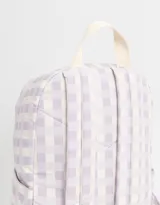 Mochila de tela con estampado a cuadros lila y blanco, con bolsillo frontal con cierre y moño bordado. Tiene correas regulables, manija superior y doble cierre superior.