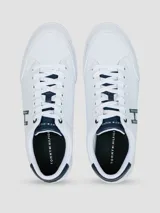 Zapatillas urbanas de corte bajo, color blanco, con cordones y suela de goma. Presentan un gran logo 'H' en color azul marino en el lateral y detalles en azul marino en el talón y la lengüeta.