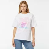 Remera blanca de algodón con estampado frontal de la lengua de The Rolling Stones y texto en color rosa y celeste.