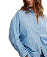 Camisa a rayas verticales color crema y marrón, de corte oversize y estilo masculino. Tiene cuello camisero, cierre frontal con botones y canesú en la espalda.