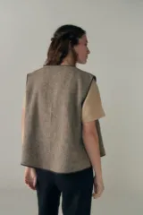 Chaleco marrón con solapas amplias y terminaciones envivadas. Diseño reversible y sin mangas.