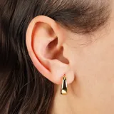 Aros tipo argolla pequeños, dorados, con forma trapezoidal o de gota invertida, de acabado liso y brillante.