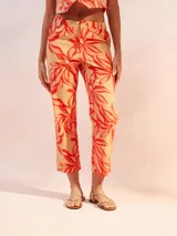 Pantalón capri color beige con estampado de hojas rojas.