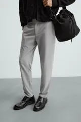 Pantalón largo de vestir gris claro con estampado de cuadros, corte slim fit y cintura elástica. Confeccionado en tejido con alta elasticidad, bolsillos frontales y cierre frontal con cremallera y botón.