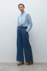 Camisa de algodón celeste claro, de manga larga, con cuello mao con volados y bordados calados florales en el frente y las mangas.