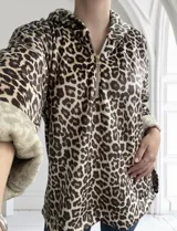 Buzo de felpa con estampado animal print en tonos marrones y crema, con cuello tipo polo y cierre frontal.