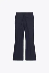 Pantalón de vestir azul marino, de tiro medio, con bolsillos delanteros y falsos bolsillos de vivo en la espalda. Pierna recta y acampanada.