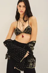 Top de bikini negro con bordado dorado y detalle de borla roja.