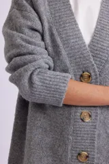 Cardigan de punto gris melange con botones marrones.
