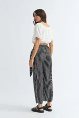 Pantalón palazzo de rayas verticales en blanco y negro, con lazo en la cintura y corte amplio.