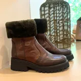 Botas cortas de cuero color marrón con caña alta y forro de piel sintética verde.