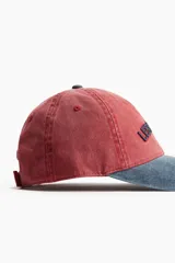 Gorra de sarga de algodón color rojo con visera azul y bordado frontal con la frase "Les Sports". Cuenta con cinta antitranspirante y hebilla metálica ajustable en la parte trasera.