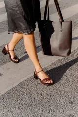 Sandalias de tacón color beige con puntera cuadrada, tiras doradas en el empeine y tobillo, y taco cuadrado.