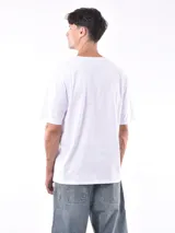 Remera gris de corte oversized, cuello redondo y mangas cortas. 