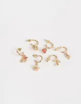 Set de seis aros dorados con argolla y dijes esmaltados: oso de peluche, corazón con texto "I Love NY", cupcake, avión, corona y manzana.