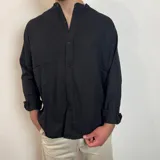 Camisa negra de manga larga con cuello mao y abotonadura frontal. Corte regular.
