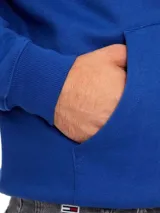 Buzo azul con capucha y cordones ajustables, bolsillo tipo canguro y logo de Tommy Jeans bordado en el pecho.