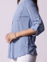Blusa celeste texturada marca Ninety, con cuello a la base, escote en V y abertura central con botones. Delantera con bolsillo y mangas tres cuartos regulables con presilla y botón.
