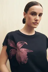 Remera blanca de manga corta con estampado de una flor color durazno en el frente.