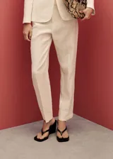 Pantalón de lino color crema, de corte recto y tiro alto, con trabillas para cinturón, bolsillos laterales y traseros.