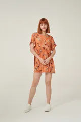 Vestido corto color naranja con estampado floral multicolor, de corte holgado y mangas cortas con volados.