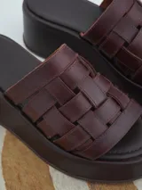 Sandalias negras de cuero con plataforma pareja y tiras de cuero tejidas en la parte superior.