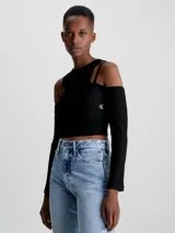 Remera Calvin Klein negra de punto canalé con doble capa y efecto 2 en 1. Tiene mangas largas con hombros descubiertos y logo bordado en el lateral. Corte slim cropped.
