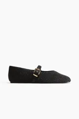 Ballerinas estilo guillerminas negras, confeccionadas en paja de plástico trenzada con ribetes en tejido revestido y tira ajustable en el empeine con hebilla dorada. Forro de punto y suela plana.