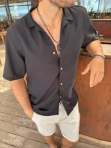 Camisa negra de fibrana con cuello solapa, manga corta y cierre frontal con botones de madera.