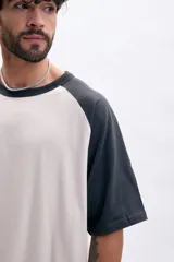 Remera manga corta con mangas ranglan en color gris oscuro y cuerpo color crema.