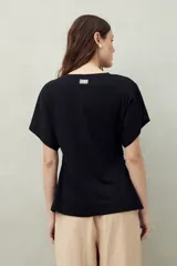 Remera blanca de manga corta con bordado frontal "C’est la vie", calce relajado y frunces laterales.