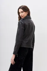 Campera de cuero ovino negra, estilo motoquero, con solapas anchas, charreteras en los hombros y cierres metálicos plateados en el frente, puños y bolsillos.