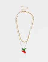 Collar corto multicadena, con una cadena dorada de eslabones grandes y otra de mostacillas blancas, con dije de cerezas rojas y hojas verdes hechas de mostacillas.