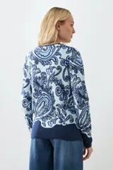 Chaqueta tejida color verde agua con estampado floral en azul marino, de corte recto y cuello redondo.