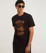 Remera negra de algodón con cuello redondo y mangas cortas. Estampa frontal con diseño de moto y texto "Brooklyn New York City 1976 Custom Motor Vintage Co.".