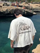 Remera amarilla con estampado en la espalda de una camioneta con una chica y una tabla de surf.