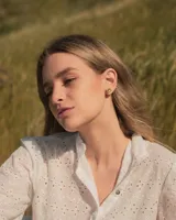 Set de dos piezas de joyería para la oreja: un arete de botón con forma orgánica irregular y un ear cuff a juego, ambos de metal dorado con acabado martillado.