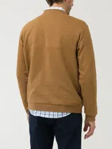 Buzo color ocre de algodón orgánico, con cuello redondo y abertura parcial con broches. Tiene un bolsillo tipo parche en el pecho con etiqueta RKF con paisaje bordado.