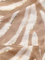 Bufanda rectangular de tela suave color beige con estampado de cebra en tonos marrones y detalles dorados.