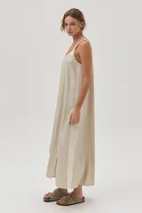Vestido largo color beige de lino metalizado, con tirantes anchos a contratono y corte recto con abertura lateral.