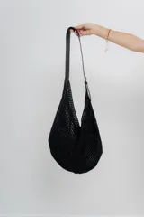 Bolso tejido color crudo con textura calada y correa de eco-cuero negra regulable con hebilla metálica.
